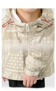 Close-up of khaki hooded jacket with white paisley pattern and red contrast drawstrings