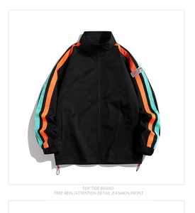 Detail of a black sports jacket featuring vibrant orange and green striped sleeves and high collar