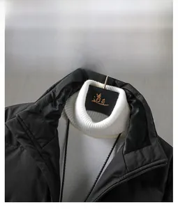 Dettaglio ravvicinato del collo alto della giacca nera e maglione bianco intrecciato