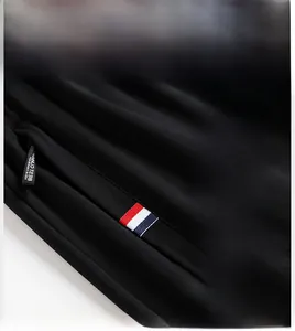 Detail of men's casual joggers featuring a zipper pocket with tri-color woven ribbon trim