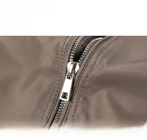 Close-up of durable silver metal zipper on the brown casual military jacket fabric