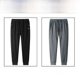 Detail of grey and black slim-fit jogger pants with zippered pockets and drawstrings