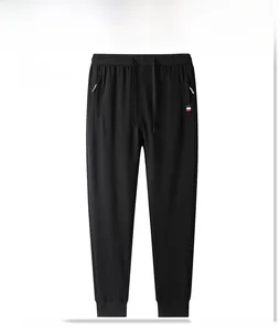 Detail of men's black joggers showing elastic drawstring waist and zippered pockets