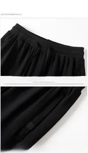 Detail of men's black joggers showing elastic waistband with drawstring and logo pocket