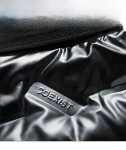 Close-up of black glossy PU fabric with COEXIST embossed logo on seamless puffer vest