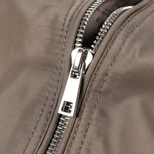 Close-up of a silver metal zipper on a brown casual jacket with high-density fabric