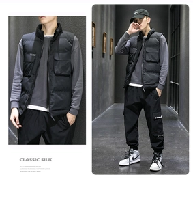 Detail view of men's black padded cargo vest with multi-pocket and stand-up collar design