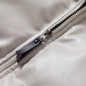Macro detail of the premium silver metal zipper and soft leather texture on beige jacket