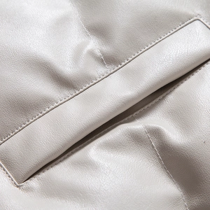 Close-up detail of pocket stitching and smooth texture on light gray faux leather jacket