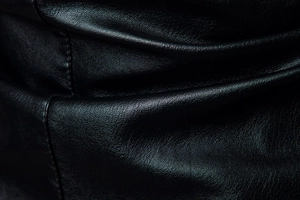 Detailaufnahme der schwarzen Lederstruktur mit hochwertigen Nähten an einer Motorradjacke