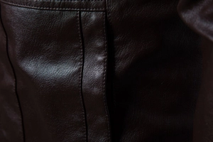 Detailansicht einer dunkelbraunen Lederjacke mit präziser Doppelnaht-Verarbeitung