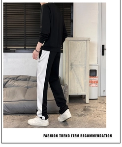Side view of men's black tracksuit showing white color-block contrast on sports pants