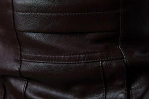 Detail der dunkelbraunen Lederjacke mit natürlicher Textur und Doppelnaht-Verarbeitung