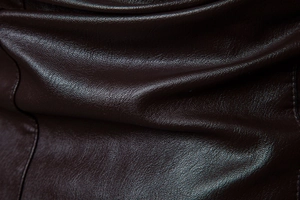 Detailaufnahme von dunkelbraunem Kunstleder mit feiner Lychee-Narbung und Glanz