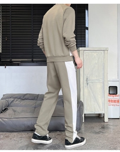 Detail view of khaki men's track suit showing side white patchwork design and fabric texture