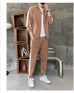 Detail of men's camel track suit featuring white side stripes on sleeve and leg