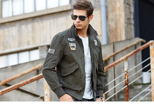 Detail of dark green military bomber jacket with embroidered aviation patches and patches