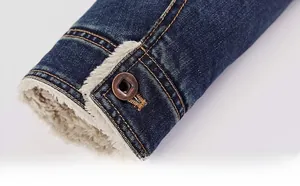 Close-up of denim jacket cuff with warm fleece lining and vintage metal button