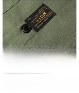 Detailed close-up of military green twill cotton fabric with MDTS woven label and button