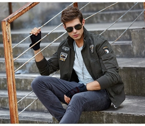 Close-up of military olive green bomber jacket with detailed embroidery patches and rugged texture