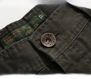 Detail of army green straight leg trousers featuring vintage metal button and woven size tag