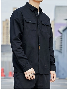 Detail of black cargo shirt featuring orange woven label and symmetrical flap pockets