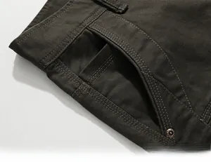 Detail of slant pocket on dark cargo pants with reinforced stitching and metal rivets