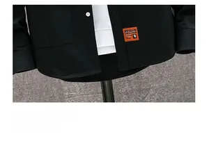 Detail of black casual shirt featuring swallowtail hem and orange decorative label