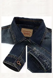 Detail of dark blue vintage wash denim jacket collar, metal cuff buttons, and pocket stitching