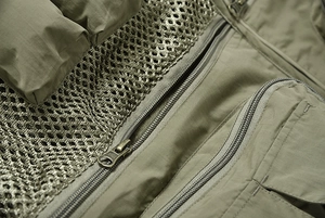 Gros plan du gilet de plein air vert avec fermetures éclair YKK en métal et tissu en maille
