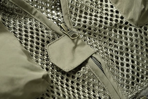 Détail macro d'une fermeture éclair YKK sur un gilet d'extérieur vert en maille aérée