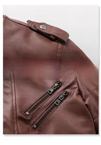 Détail de la veste en cuir marron avec boutons pression à l'épaule et double fermeture éclair