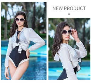 Detail of a black one-piece swimsuit paired with a white translucent sun protection cover-up