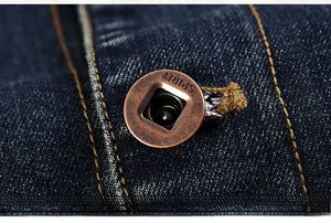 Close-up of vintage bronze metal button with SPIRIT engraving on heavy denim jacket