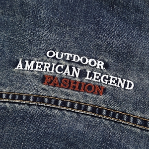 Close-up of outdoor embroidery and double yellow stitching on navy denim jacket