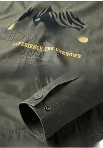 Detail of army green jacket showing metal snap buttons and printed chest logo graphic