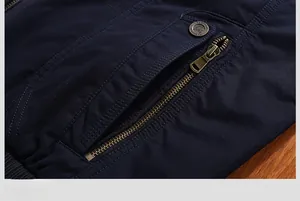 Detail of a deep blue jacket featuring a bronze metal zipper pocket and fashion button