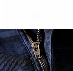 Detailed macro view of a durable bronze metal YKK zipper on dark blue canvas fabric