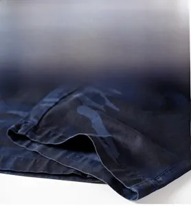 Close-up of the double-stitched hem on camo shorts showing cotton twill fabric texture