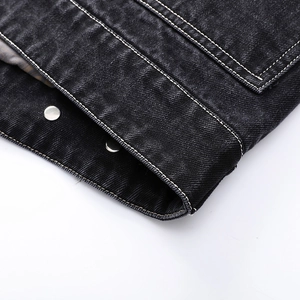 Close-up of black washed denim jacket with white stitching and silver metal buttons