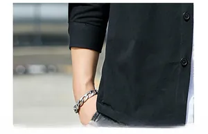 Detail of black cotton shirt cuff with round button and silver chain bracelet accessory