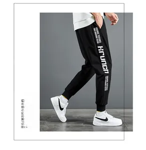 Détail d'un pantalon de jogging noir avec typographie latérale et chevilles côtelées