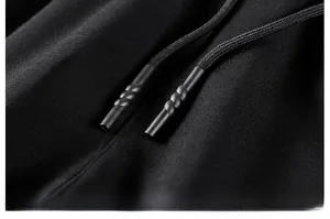 Détail du cordon de serrage noir avec embout texturé sur le pantalon en coton