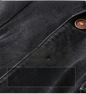 Macro shot of dark denim fabric with a vintage brown classic style button and stitching