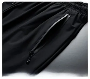 Detail of men's athletic pants showing elastic waist and waterproof zipper side pocket