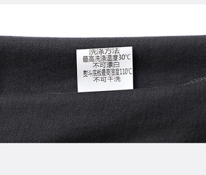 Close-up of durable stitching and white laundry care label on black cotton t-shirt