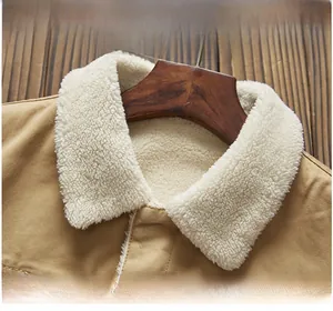 Detailed close-up of khaki canvas jacket with white faux shearling collar and metal buttons