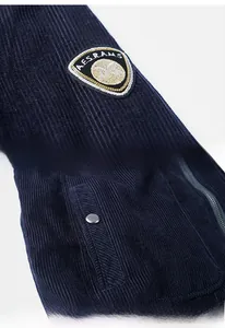 Detail of navy corduroy jacket showing embroidered arm patch and snap button pocket
