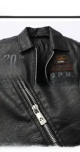 Detailed macro view of black faux leather flight jacket with vintage embroidery patches