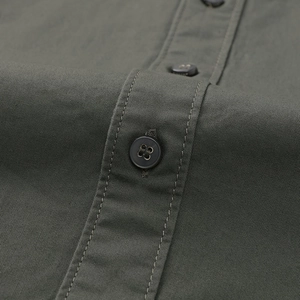Gros plan d'une chemise vert olive en sergé de coton avec coutures renforcées et bouton en résine